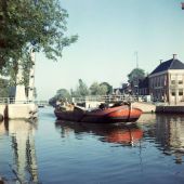 ingezonden door Hillie Kasmarek-Boskma - Herke Boskma vaart vanuit de Zuidergracht door de Woudpoortbrug in Dokkum met een bijzondere vracht ... drogende luiers van dochter Anneke, 1957
